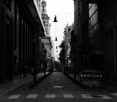 Black and white photograph of a narrow city street with historic architecture.