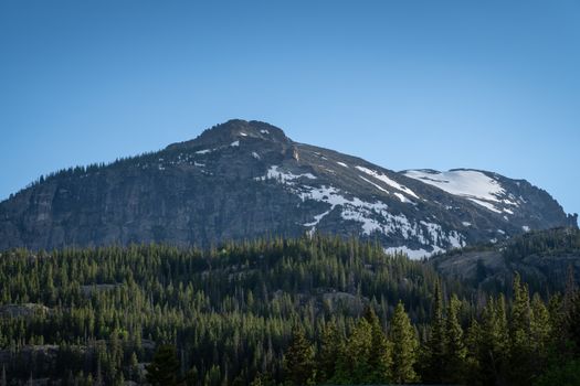 Breathtaking view of the Rocky Mountains with snow-capped peaks and lush green forest in Colorado.
