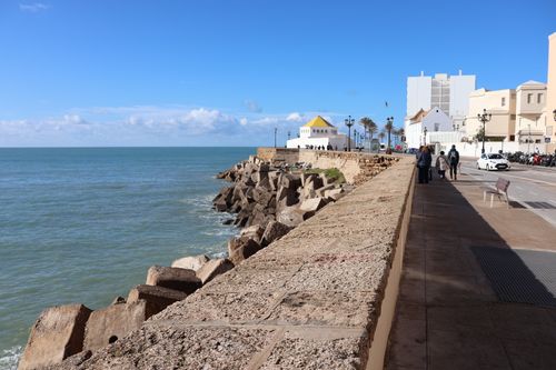 Free Sunlit promenade in Cádiz, Spain with people walking along the scenic ocean view. Stock Photo