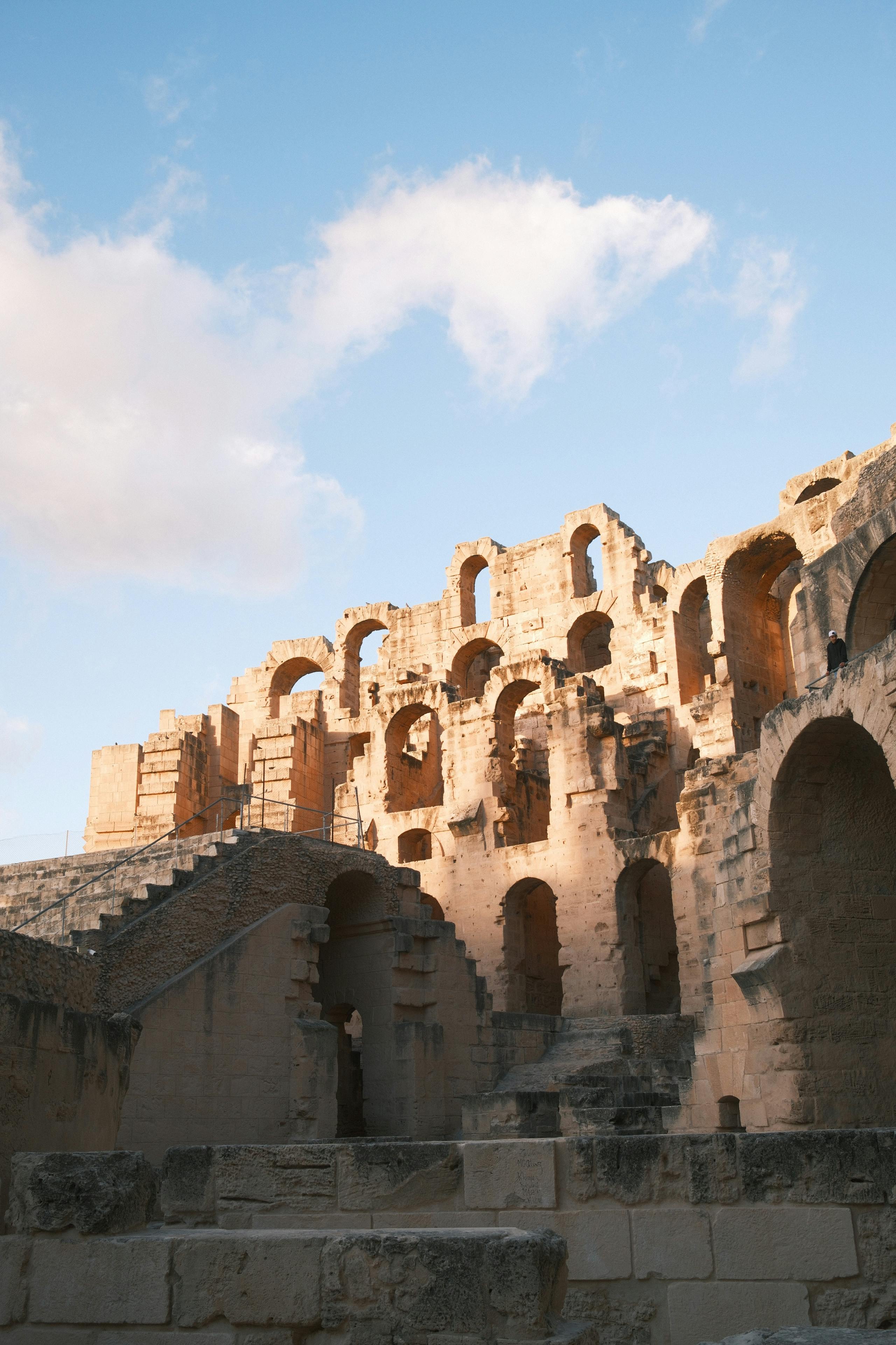 Ücretsiz Gün batımının sıcak, altın sarısı tonlarında, El Jem amfitiyatrosunun kadim ihtişamını keşfedin. Stok Fotoğraflar
