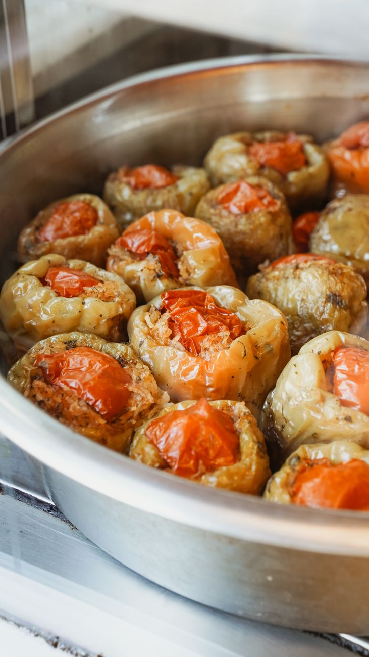 Golden-brown rocoto relleno peppers stuffed with chicken and cheese, sitting in creamy yellow aji amarillo sauce in a white baking dish