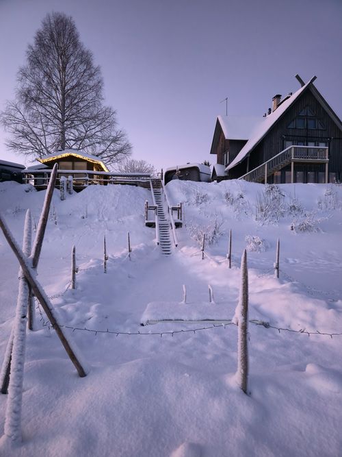 Free Cozy cabin surrounded by a serene snowy landscape at twilight, perfect winter escape. Stock Photo