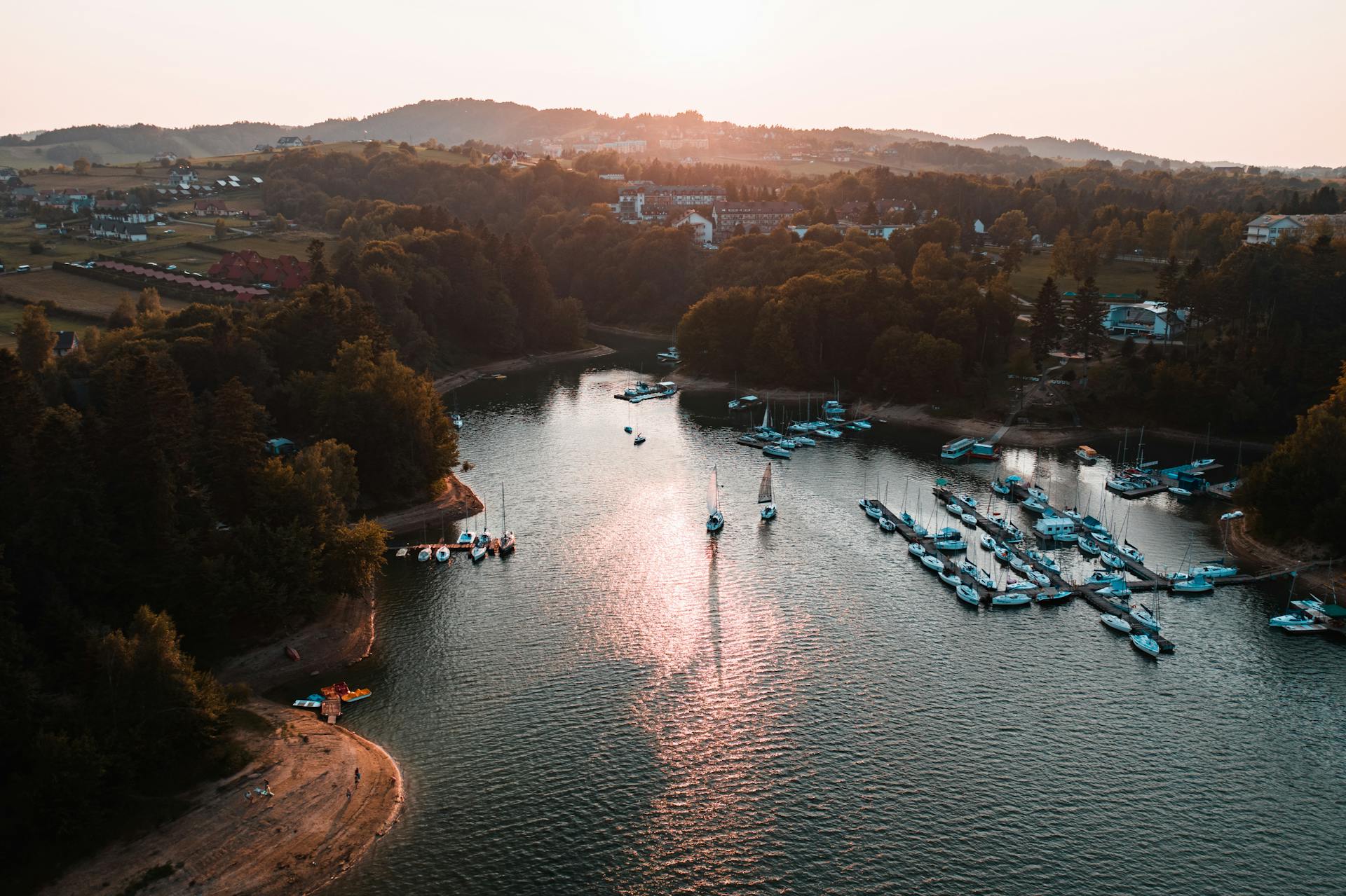 A beautiful aerial view of a peaceful marina at sunset with boats docked in calm waters.