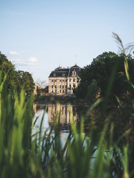 宁静的湖泊倒映着风景如画的城堡，四周环绕着郁郁葱葱的绿植