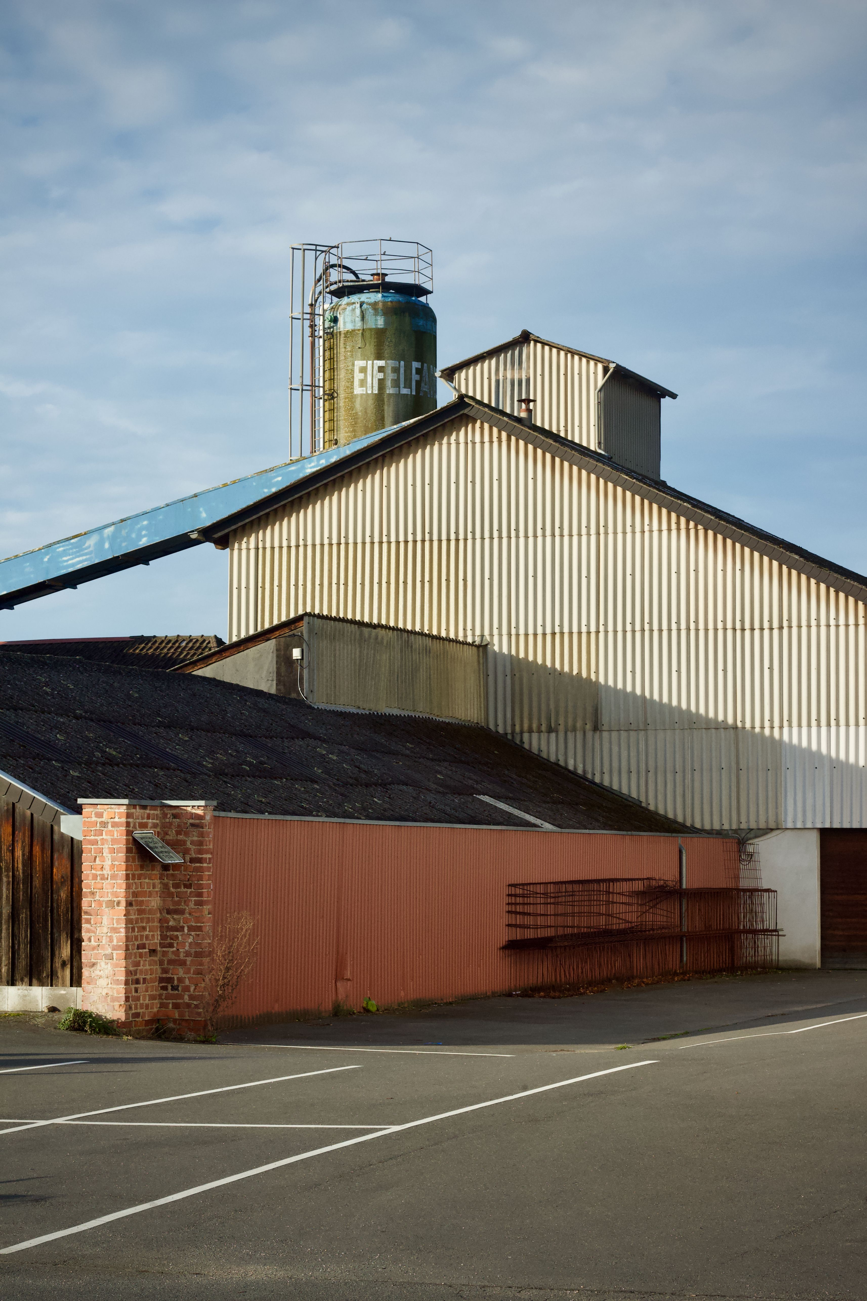 A large industrial warehouse with an Eiffel marked tank under a clear blue sky.