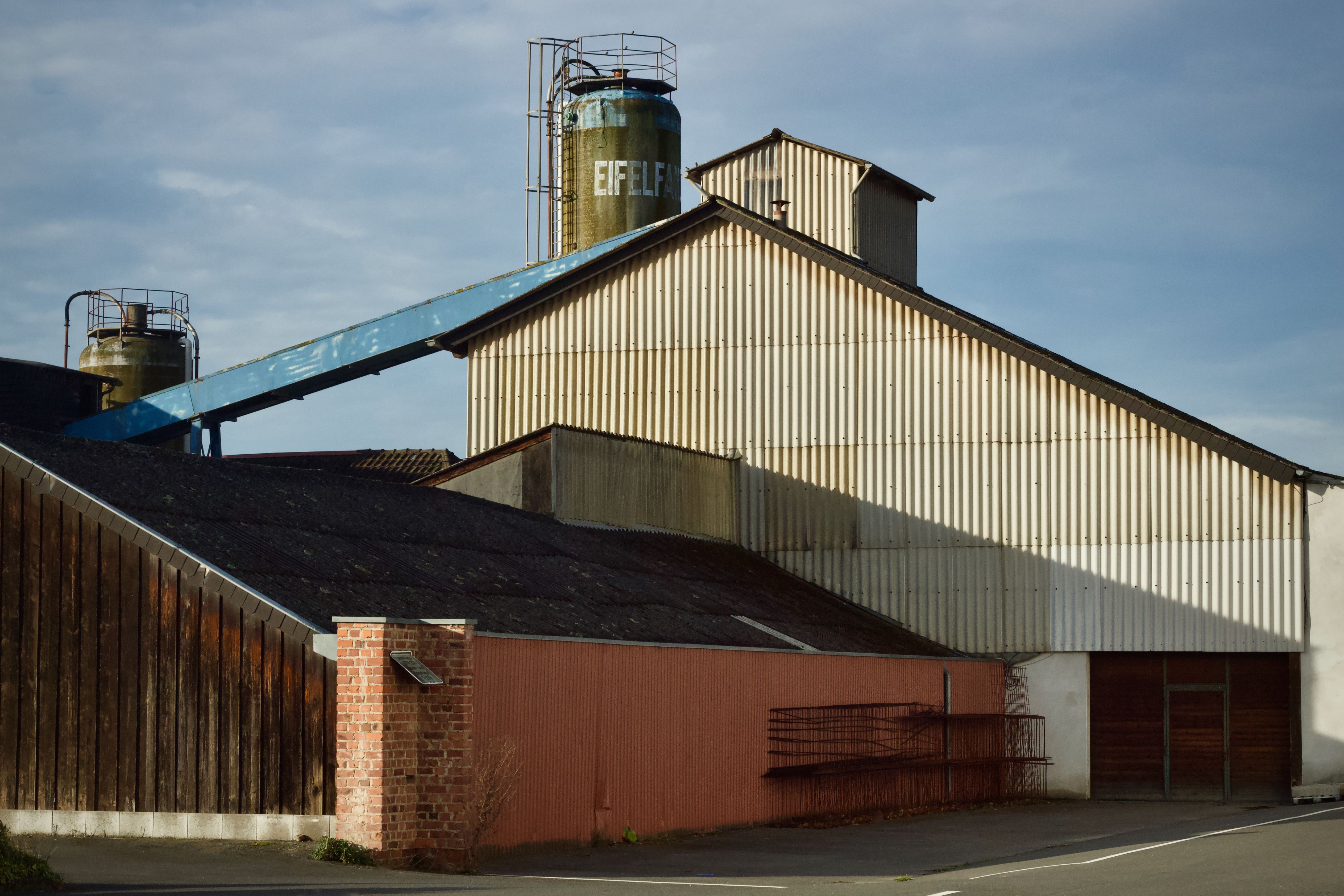 An industrial warehouse featuring silos marked 'EIFFEL' under a blue sky.