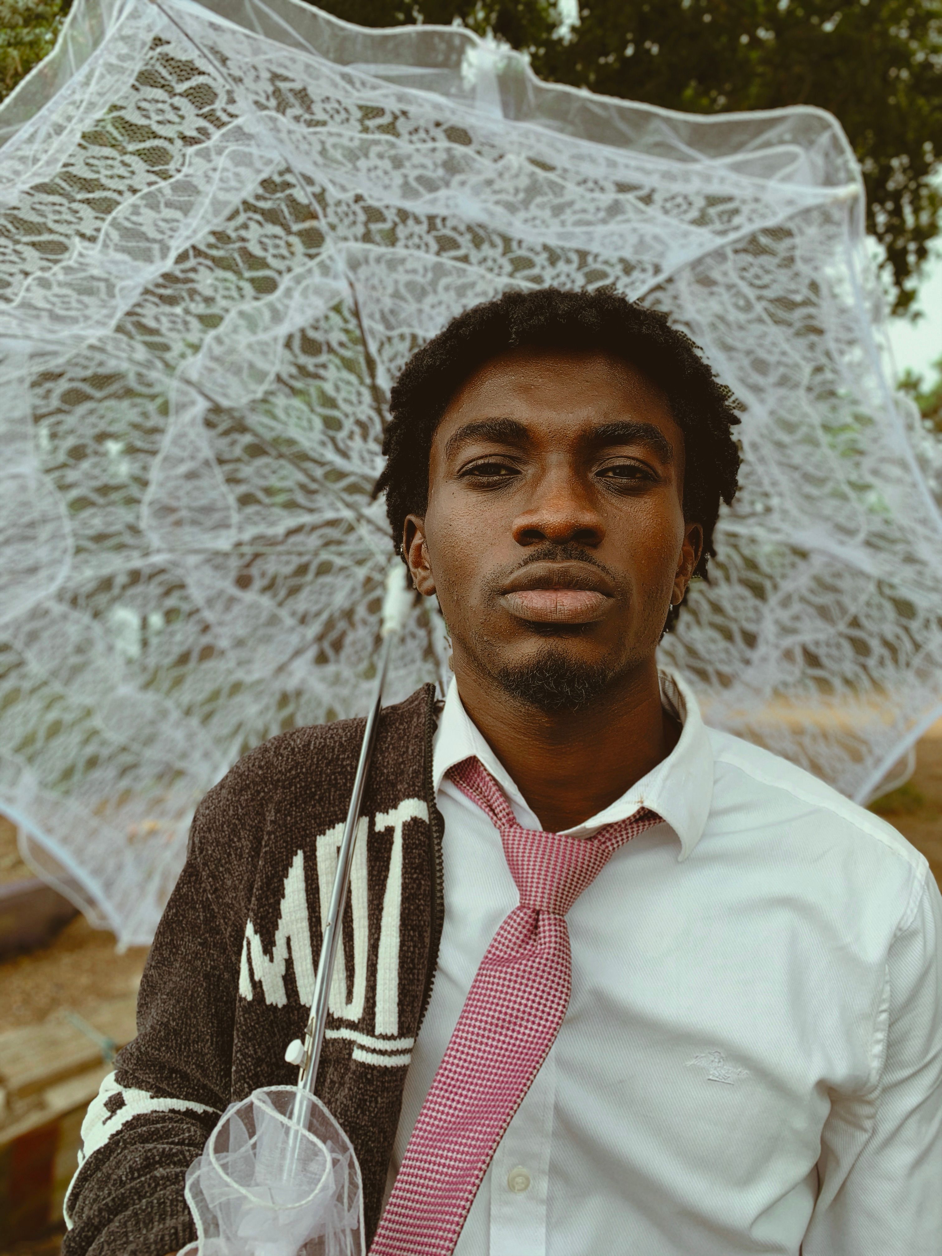Portrait of a fashionable man holding a lace umbrella outdoors.