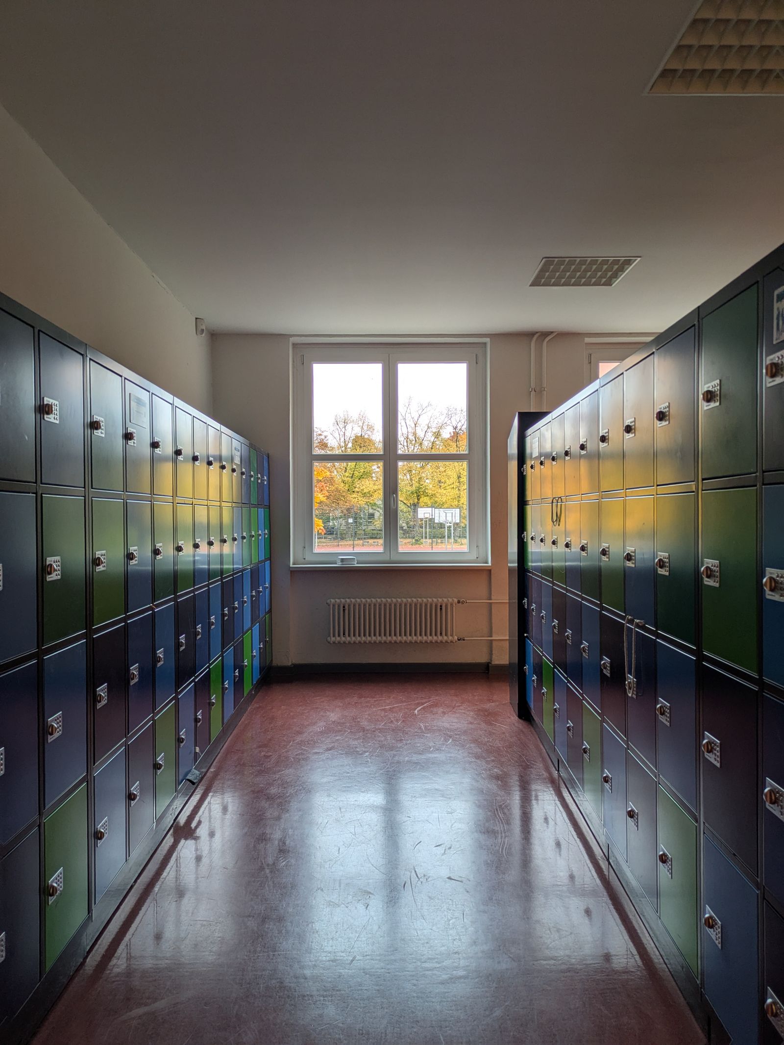 A sunny school hallway lined with vibrant, colorful lockers and no people in the frame, a real stock photo that sets the scene for Hollywood Arts, the Victorious spin-off about a performing arts high school