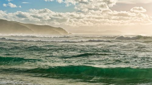 Free Captivating waves crash along the coast of Galicia, Spain under a dramatic sunset. Stock Photo