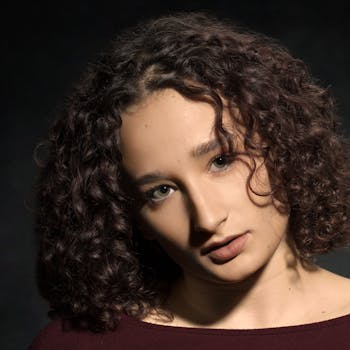 Elegant portrait of a woman with curly hair in a studio setting, capturing a classic mood.