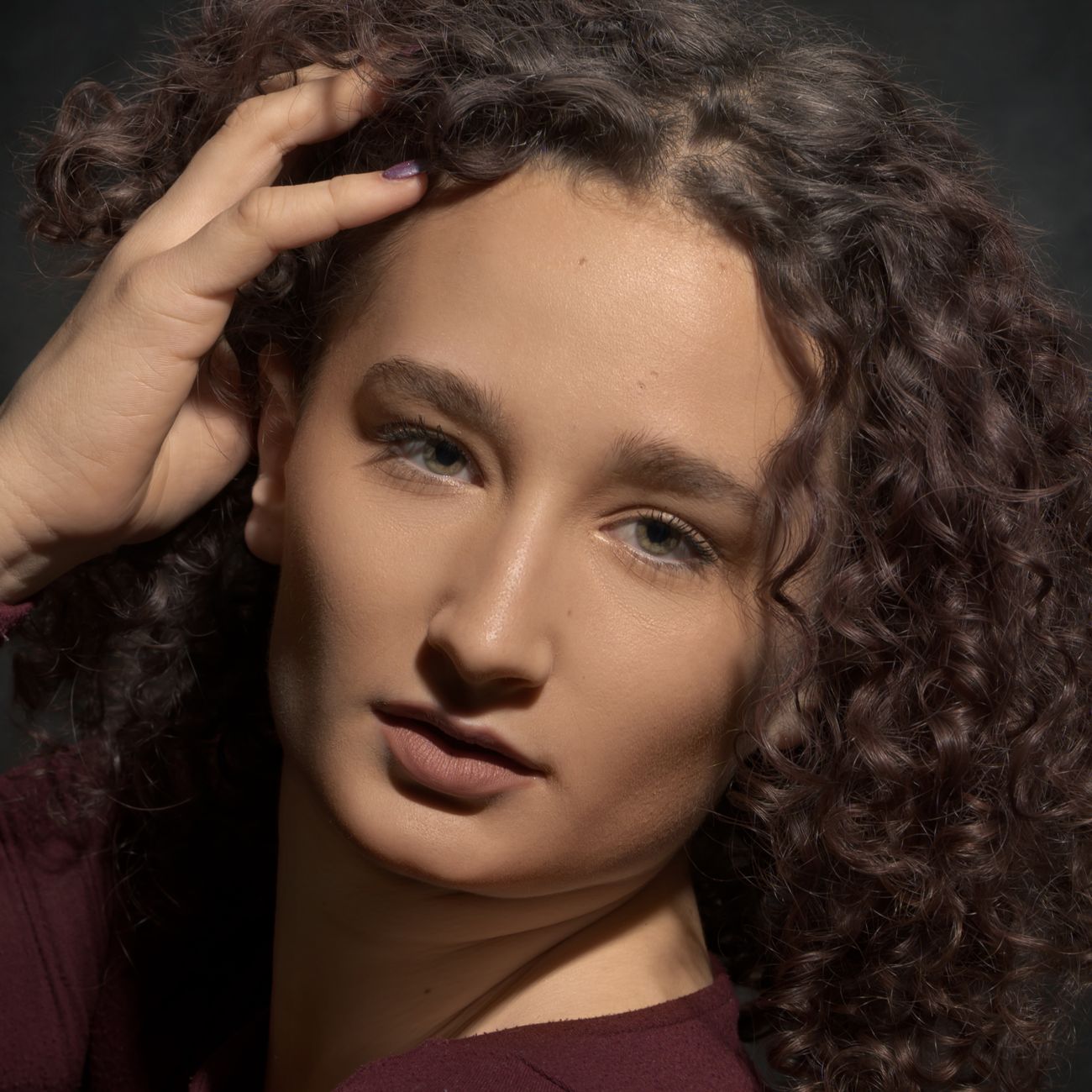 A close-up portrait of a woman with curly hair in Lyon, France, showcasing natural beauty and expression.