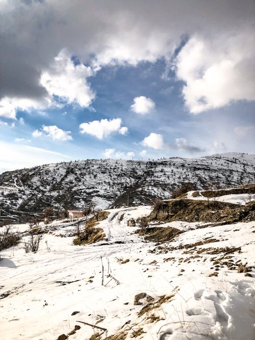 Free Scenic view of snow-covered mountains under a partly cloudy sky. Stock Photo