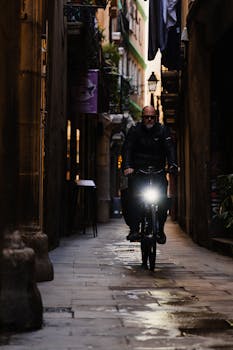 A cyclist rides through a narrow, atmospheric alley in Barcelona, Spain, showcasing urban exploration and night city life.