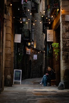 Discover the moody allure of a historic Barcelona alley illuminated by string lights.
