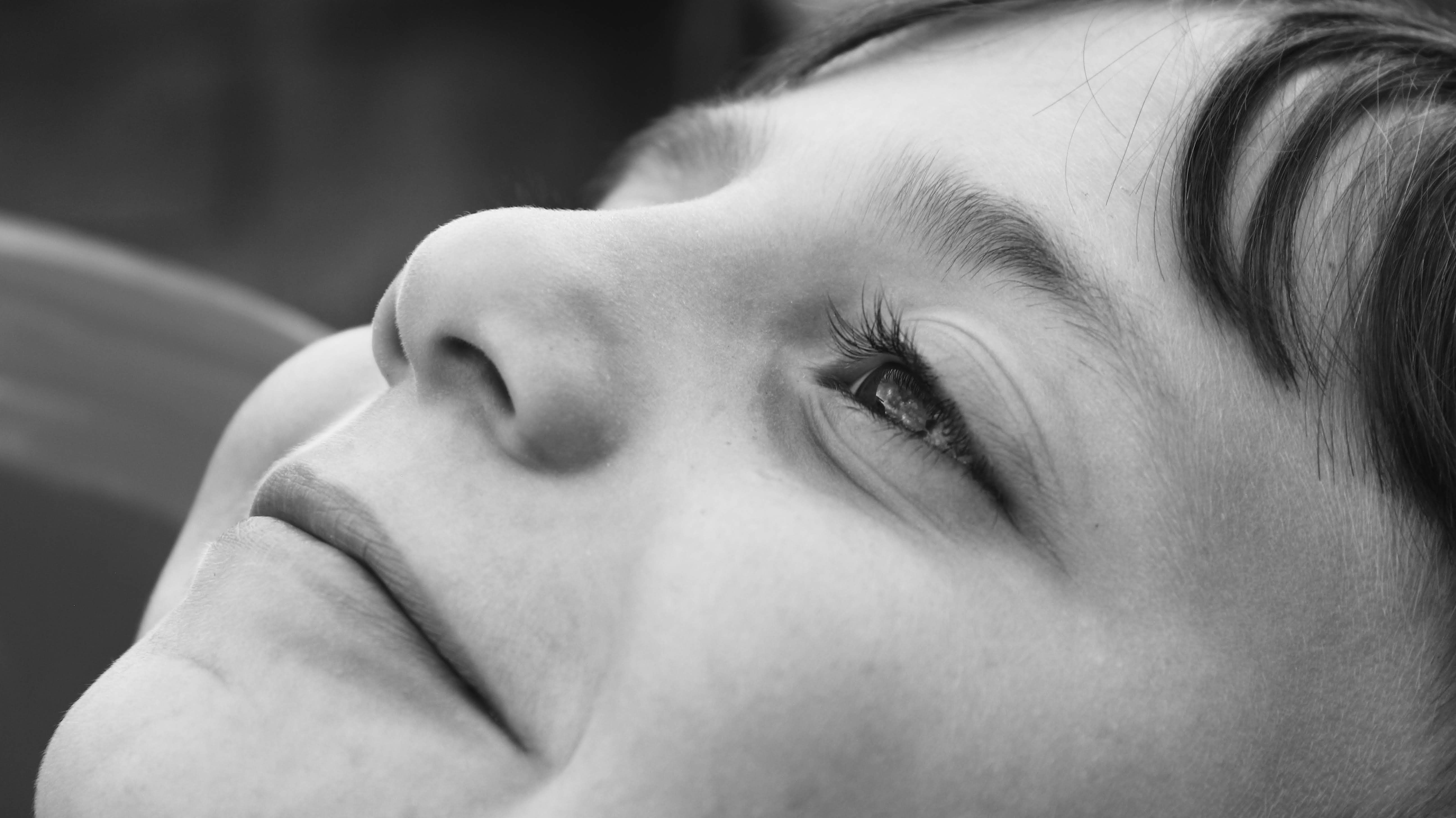 Close-up black and white portrait of a smiling child looking skyward in İstanbul, Türkiye.