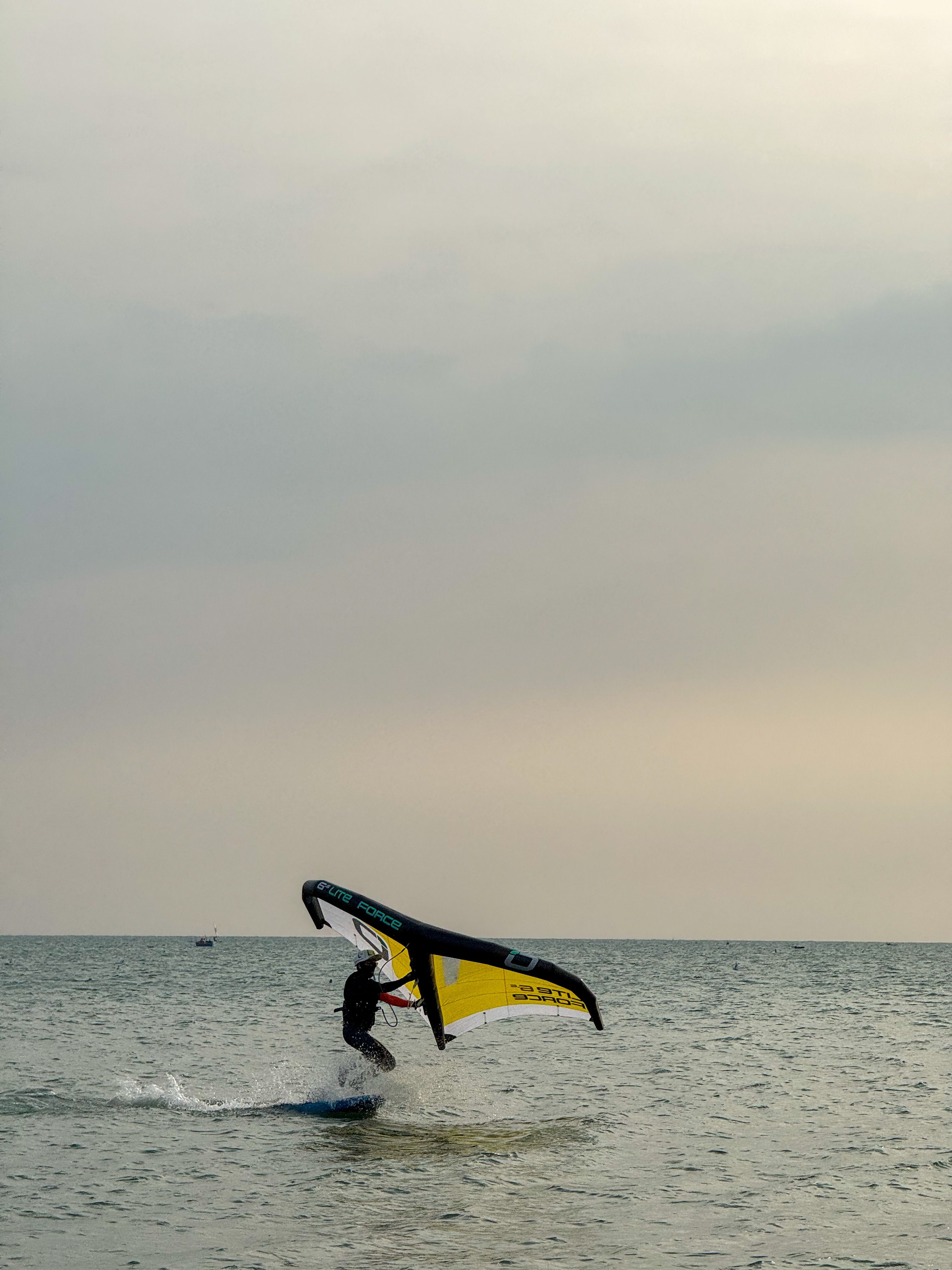 A windsurfer catching waves along Phan Thiet beach under a calm sky.