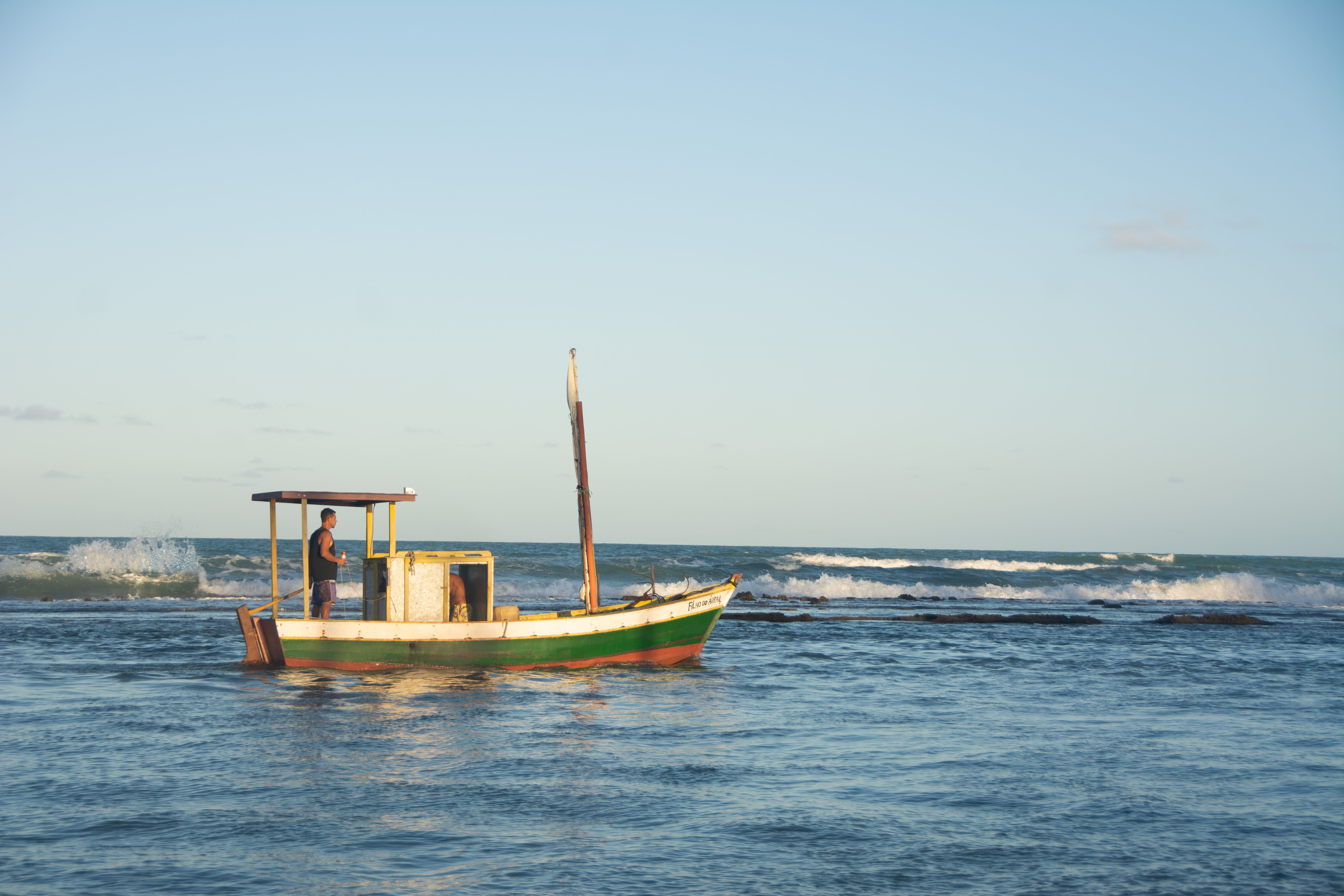 A lone fishing boat with a fisherman at sea during a serene day in Porto Seguro, Brazil.