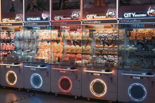 Vibrant claw machines filled with plush toys in an illuminated arcade environment.