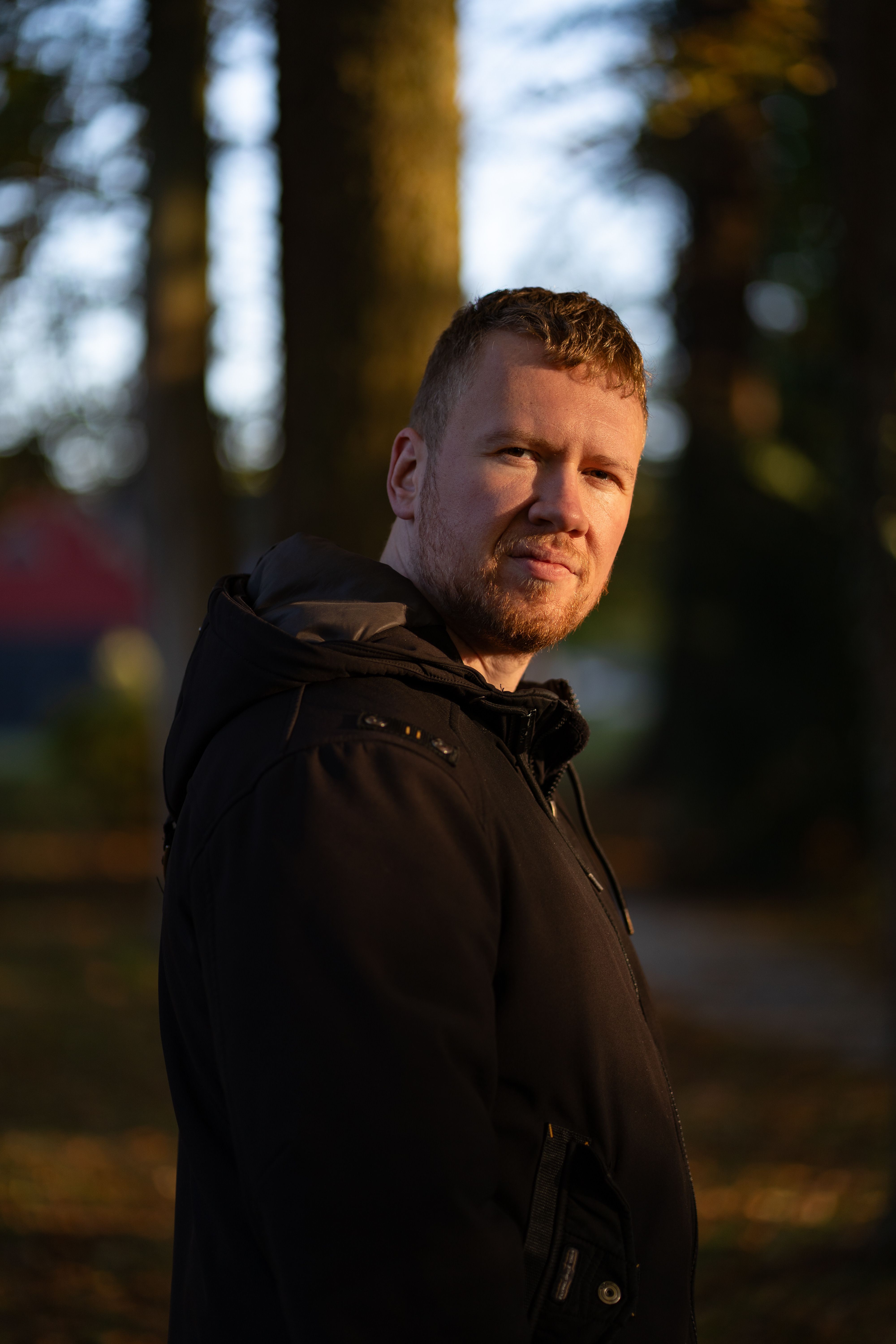 Pensive man in autumnal forest, soft light and shadows.
