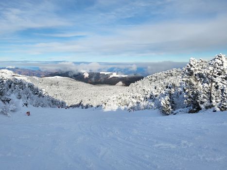 Breathtaking view of snow-covered mountains and ski slopes under a clear sky.