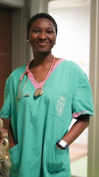 Confident female nurse smiling with stethoscope in hospital corridor. Medical professional in scrubs.