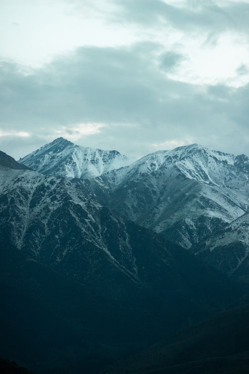 Free A breathtaking view of majestic snow-covered mountains under a cloudy sky in Kyrgyzstan, perfect for nature lovers. Stock Photo