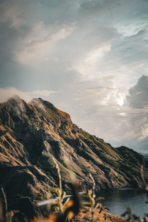 Free Scenic view of rugged mountains in East Nusa Tenggara, Indonesia, under dramatic cloudy sky. Stock Photo