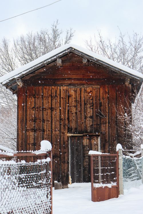 Free A rustic wooden barn surrounded by snow, showcasing a serene winter landscape. Stock Photo