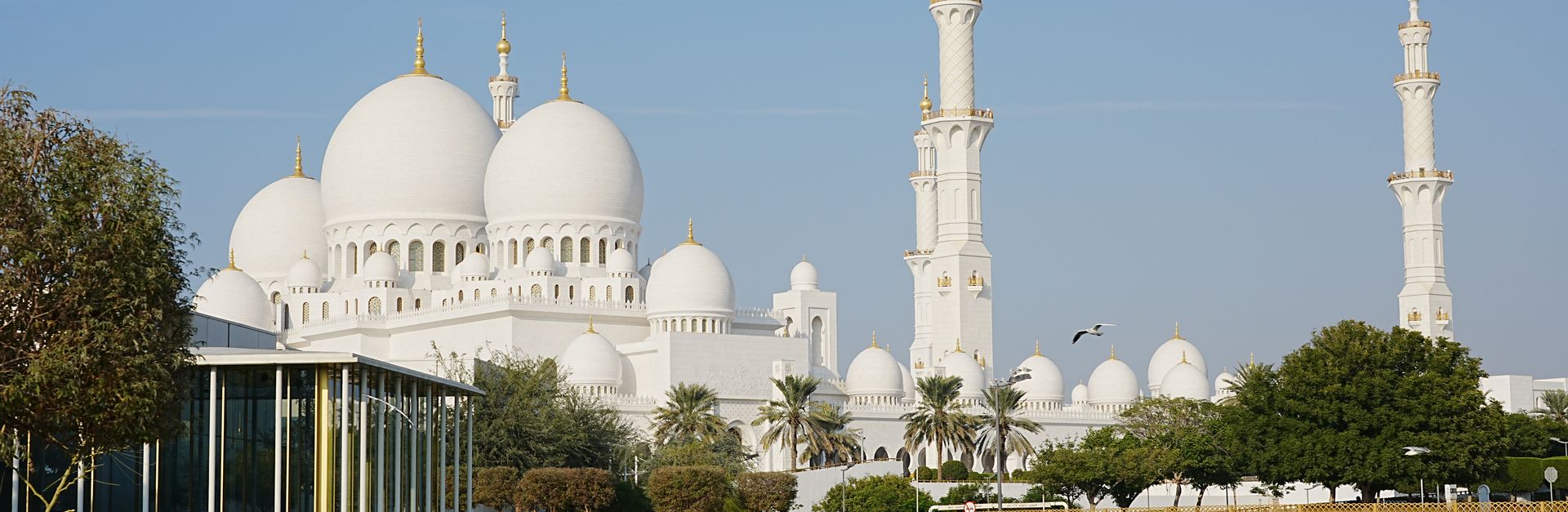 The majestic Sheikh Zayed Grand Mosque in Abu Dhabi with serene pond reflections under a clear sky.