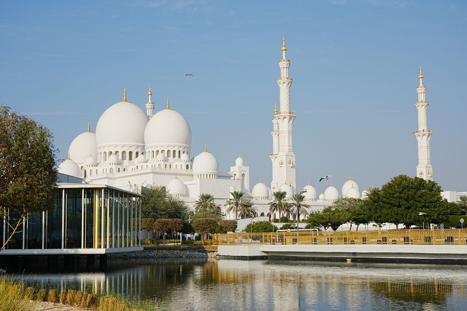 The majestic Sheikh Zayed Grand Mosque in Abu Dhabi with serene pond reflections under a clear sky.