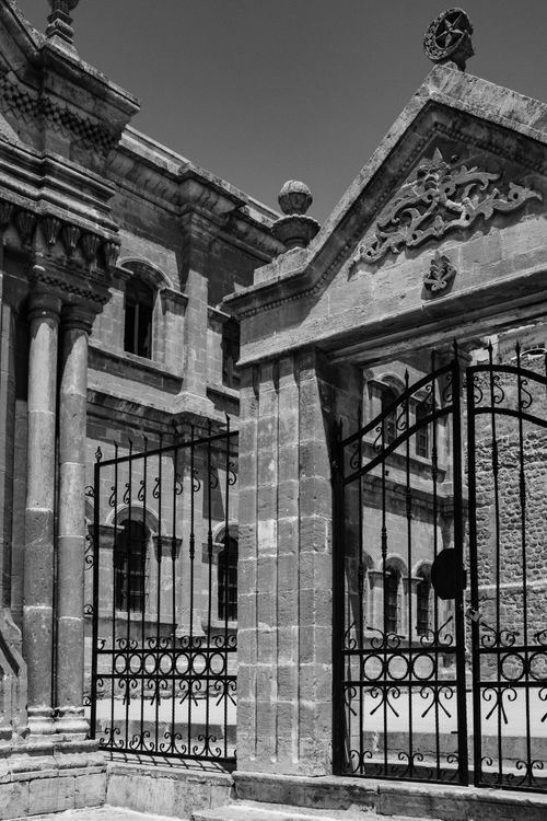 Free Black and white photo of historic stone architecture and ornate iron gate. Stock Photo