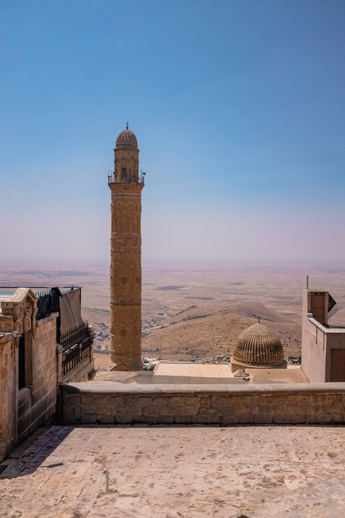 Free Scenic view of historic minaret and dome architecture over arid Turkish landscape under clear blue sky. Stock Photo