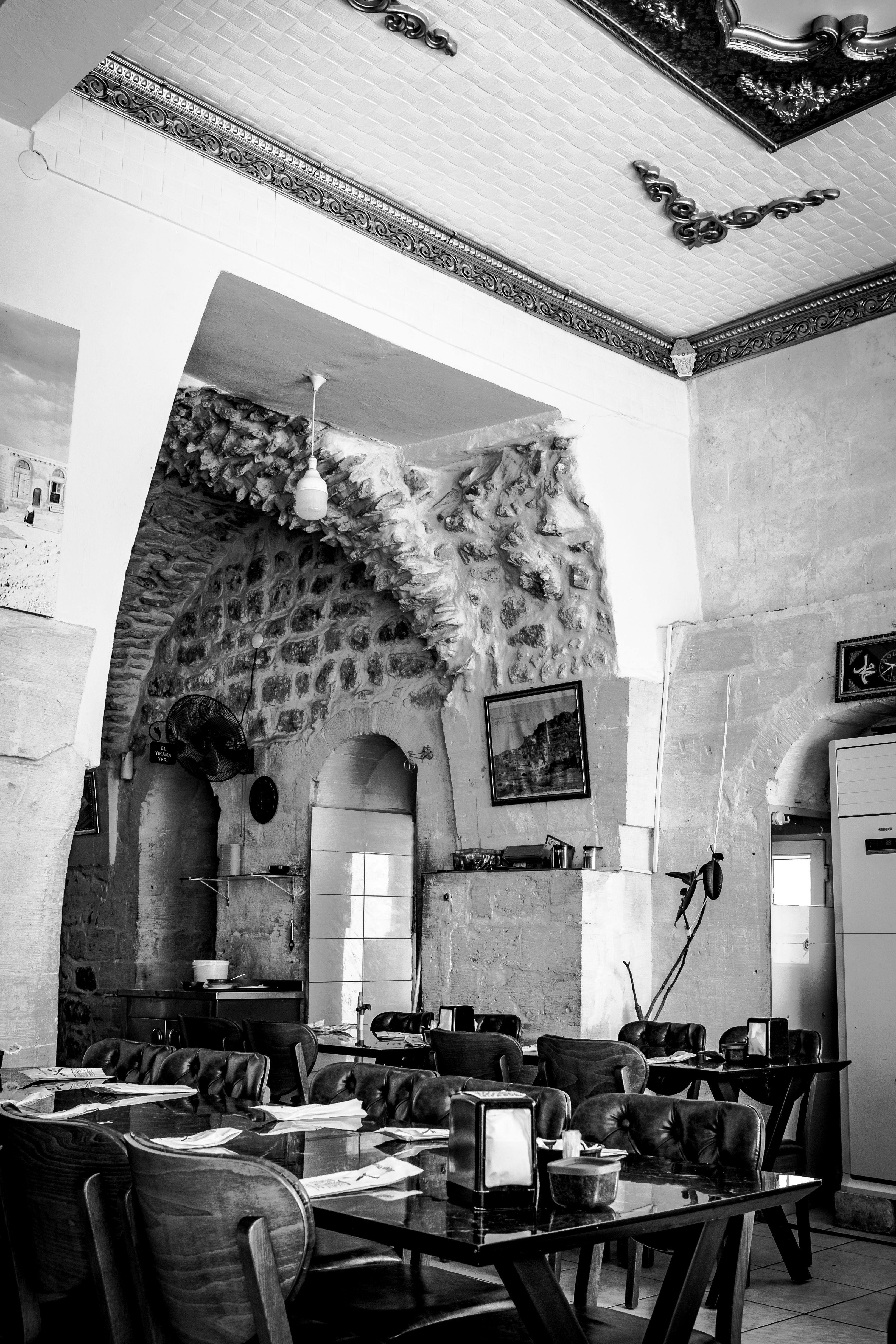 Rustic cafe interior with stone architecture and wooden furniture in black and white.