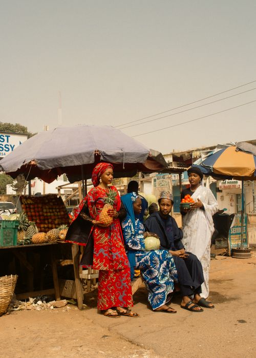 Free A bustling outdoor African market scene featuring vendors in traditional attire selling fresh produce under umbrellas. Stock Photo