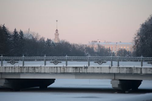 Free A serene winter scene featuring a snow-covered bridge and distant landmarks at dusk. Stock Photo
