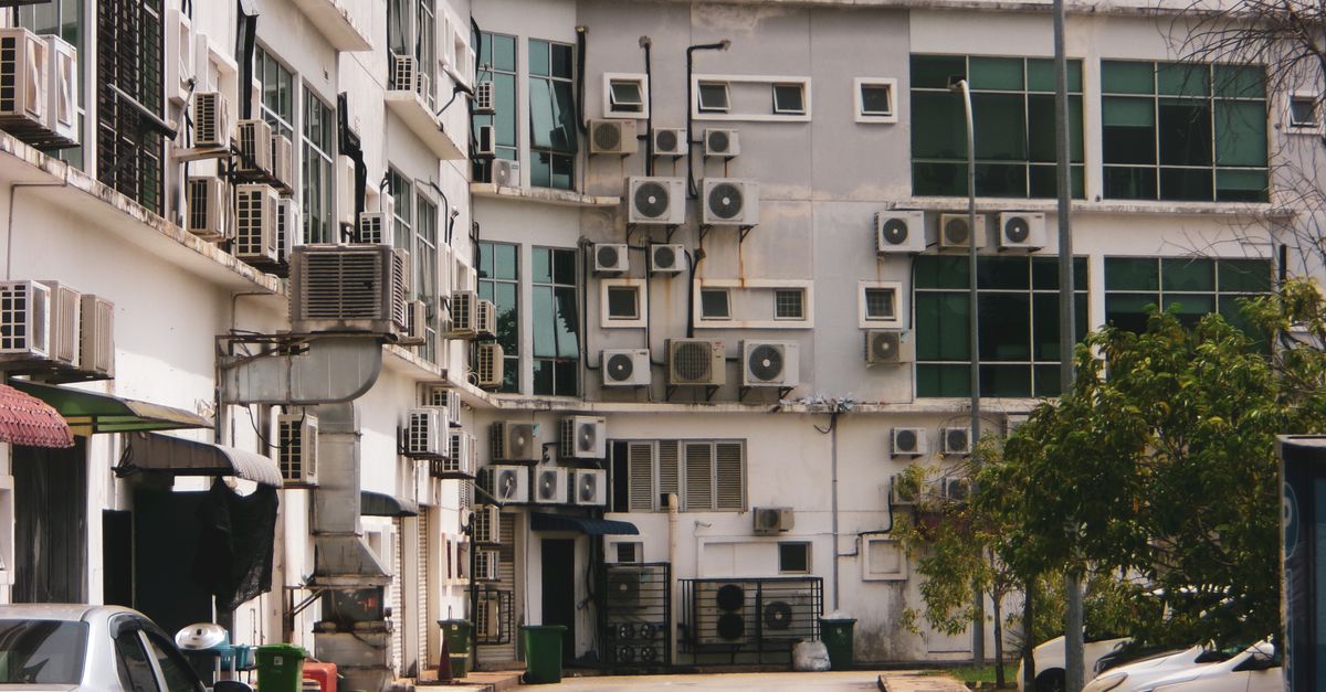 Exterior view of a building with multiple air conditioners and parked cars