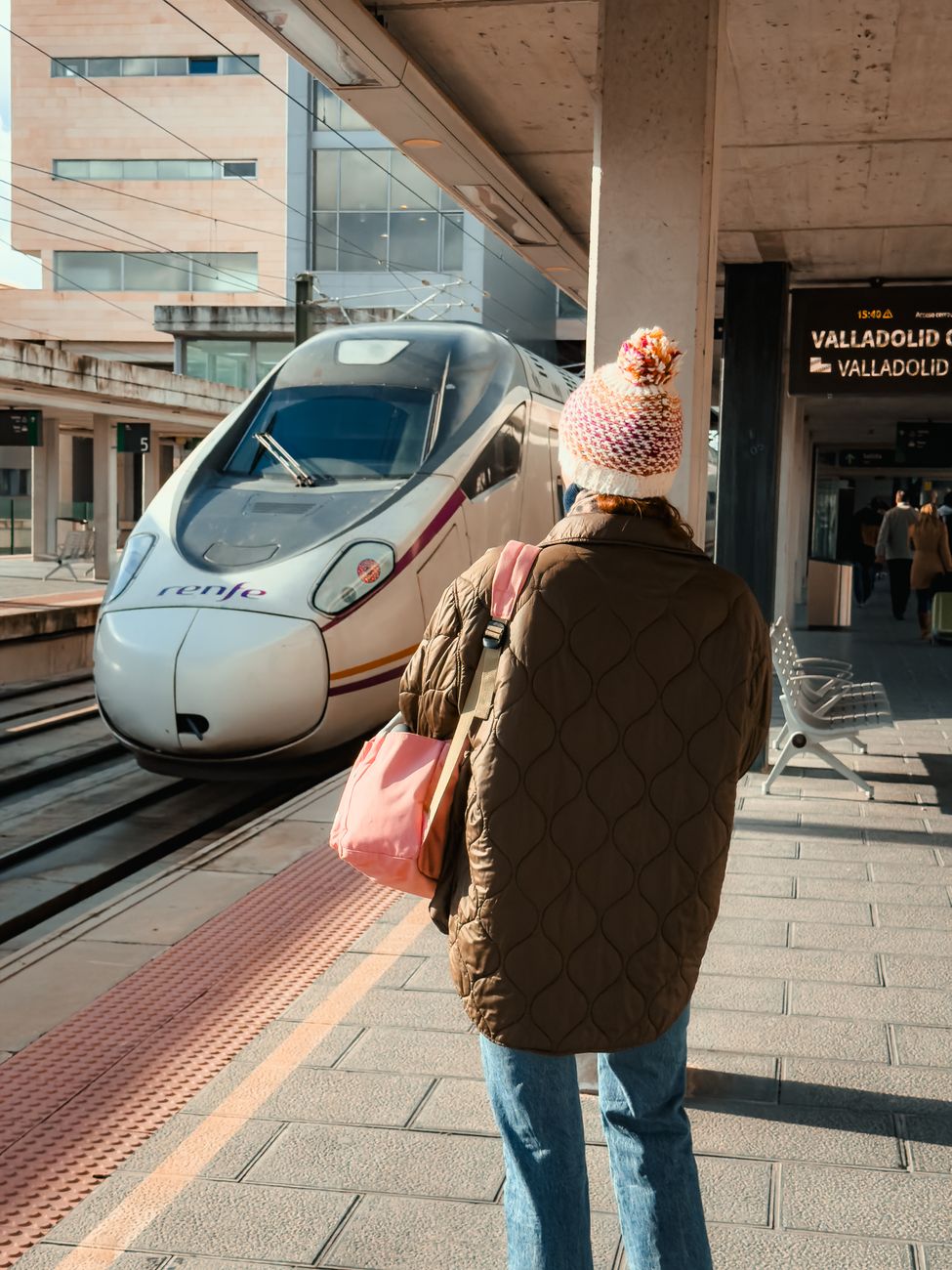 Een reiziger wacht in de winter op de komst van een moderne trein op station Valladolid.