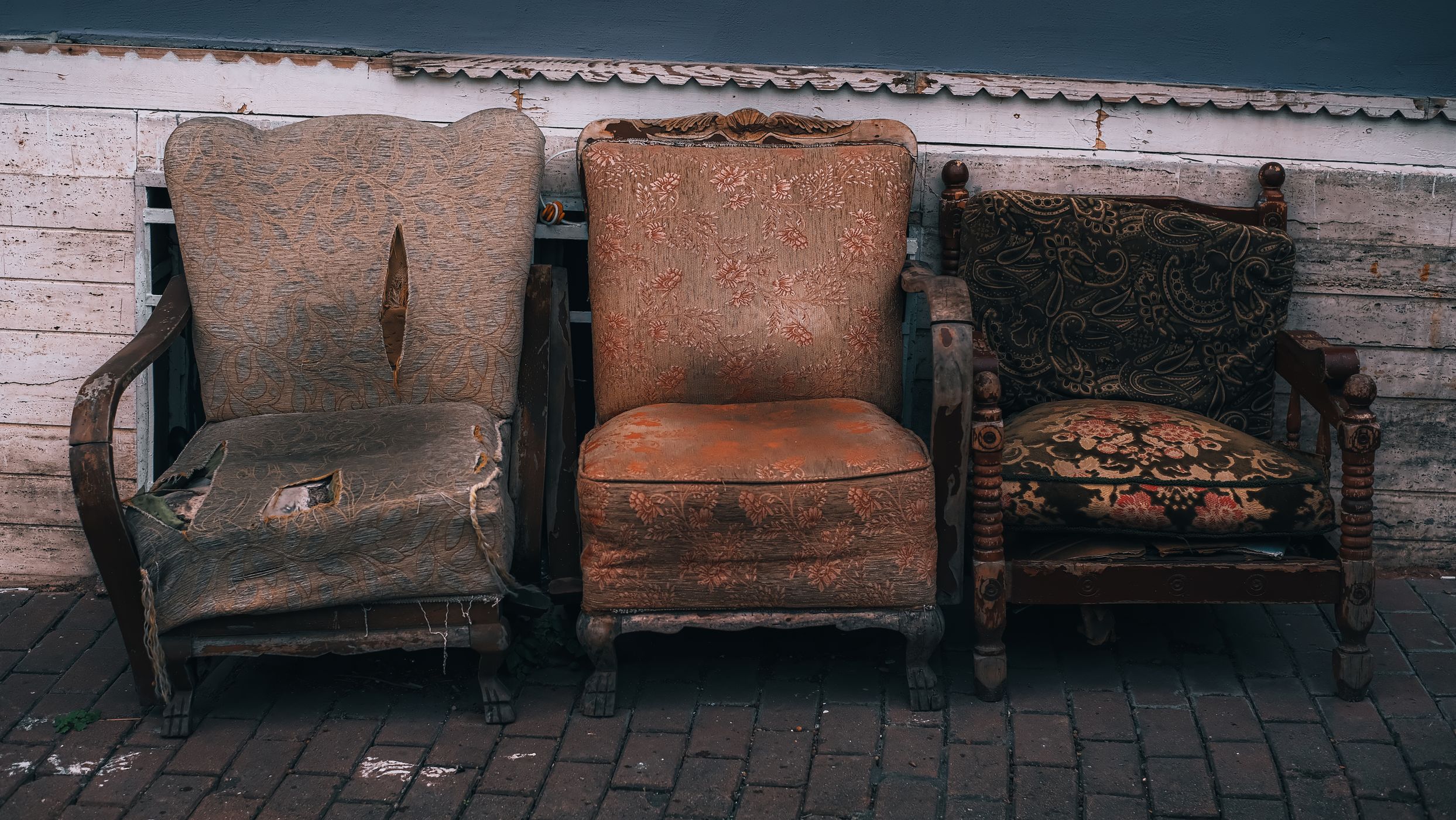 Three vintage wooden chairs against a wooden wall