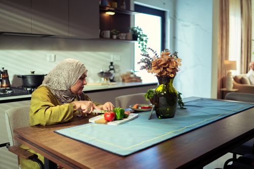 Free A Middle Eastern woman chops vegetables in a contemporary kitchen, creating a vibrant dish. Stock Photo