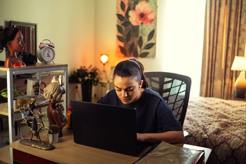 Free A woman intensely working on a laptop at her home office desk, surrounded by decor. Stock Photo