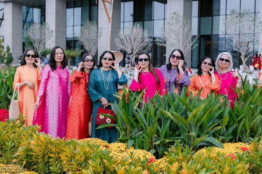 A joyful group of women in vibrant dresses posing outdoors surrounded by lush greenery.