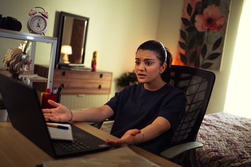Free Young woman expressing frustration while facing a laptop in a home office setting. Stock Photo
