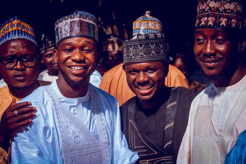 Free Group of men in traditional attire smiling together at a cultural event. Stock Photo
