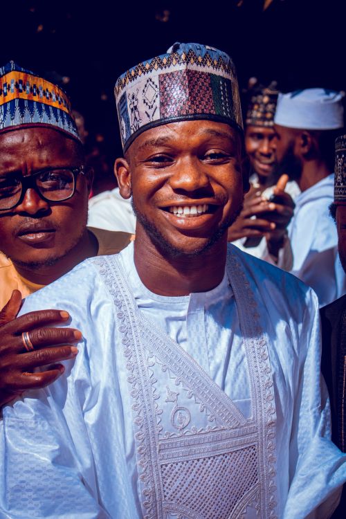Free Cheerful man in traditional clothing smiling at an outdoor event with others around him. Stock Photo