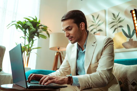 Businessman working on laptop in modern home office setting, showcasing remote work lifestyle.