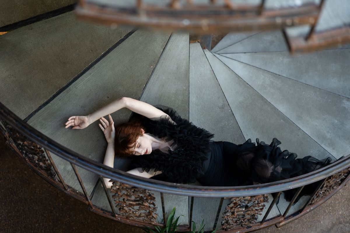 An elegant woman in a black dress on a spiral staircase — the sleek, minimalist black dress
