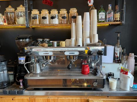 Commercial espresso machine in a cozy coffee shop with cups and jars of ingredients.