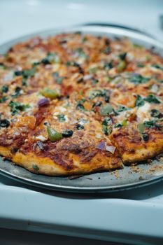 Close-up of a freshly baked veggie pizza with toppings on a tray. Perfect for foodies.