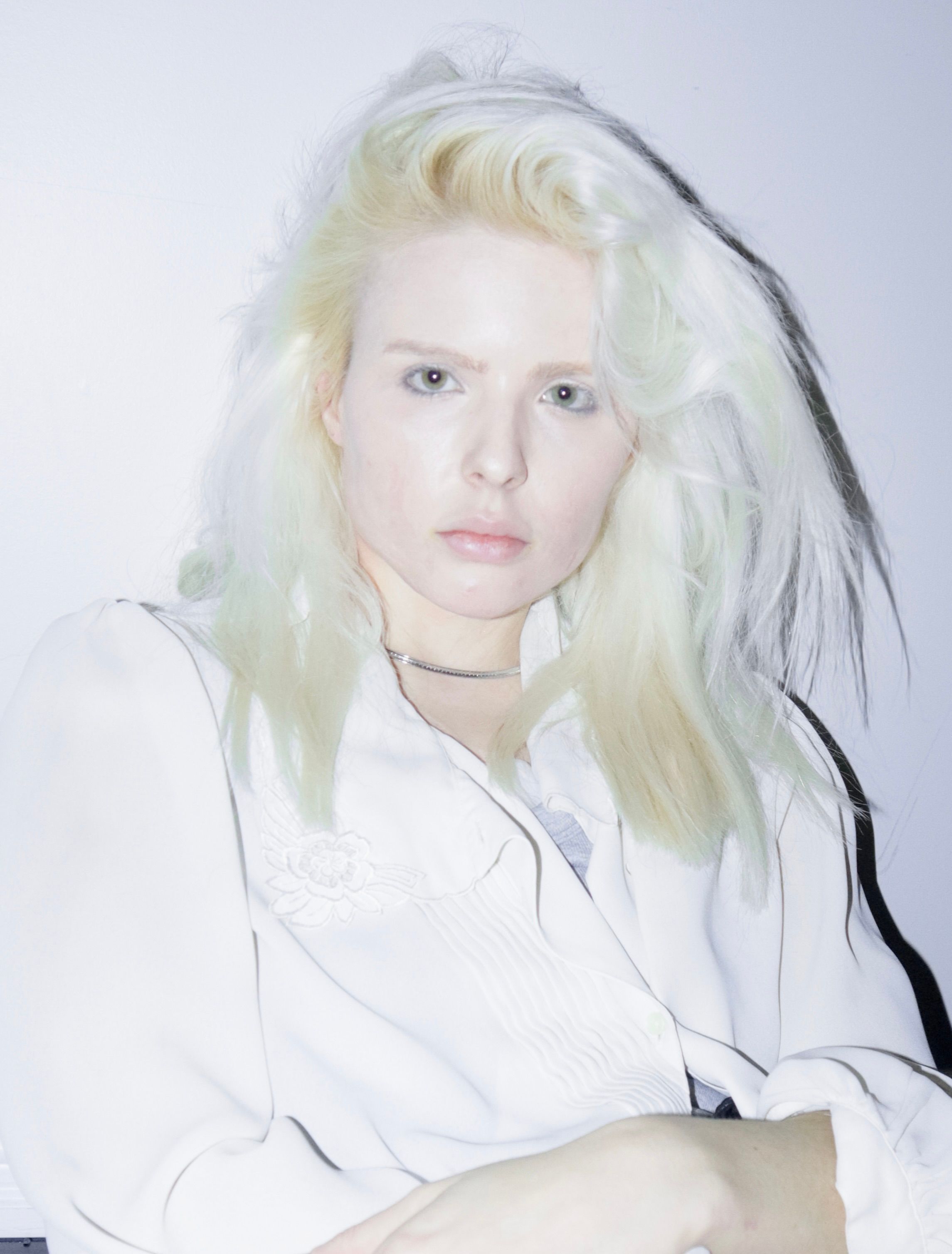 Soft light portrait of a young woman with blonde hair in a white shirt, exuding a modern aesthetic.