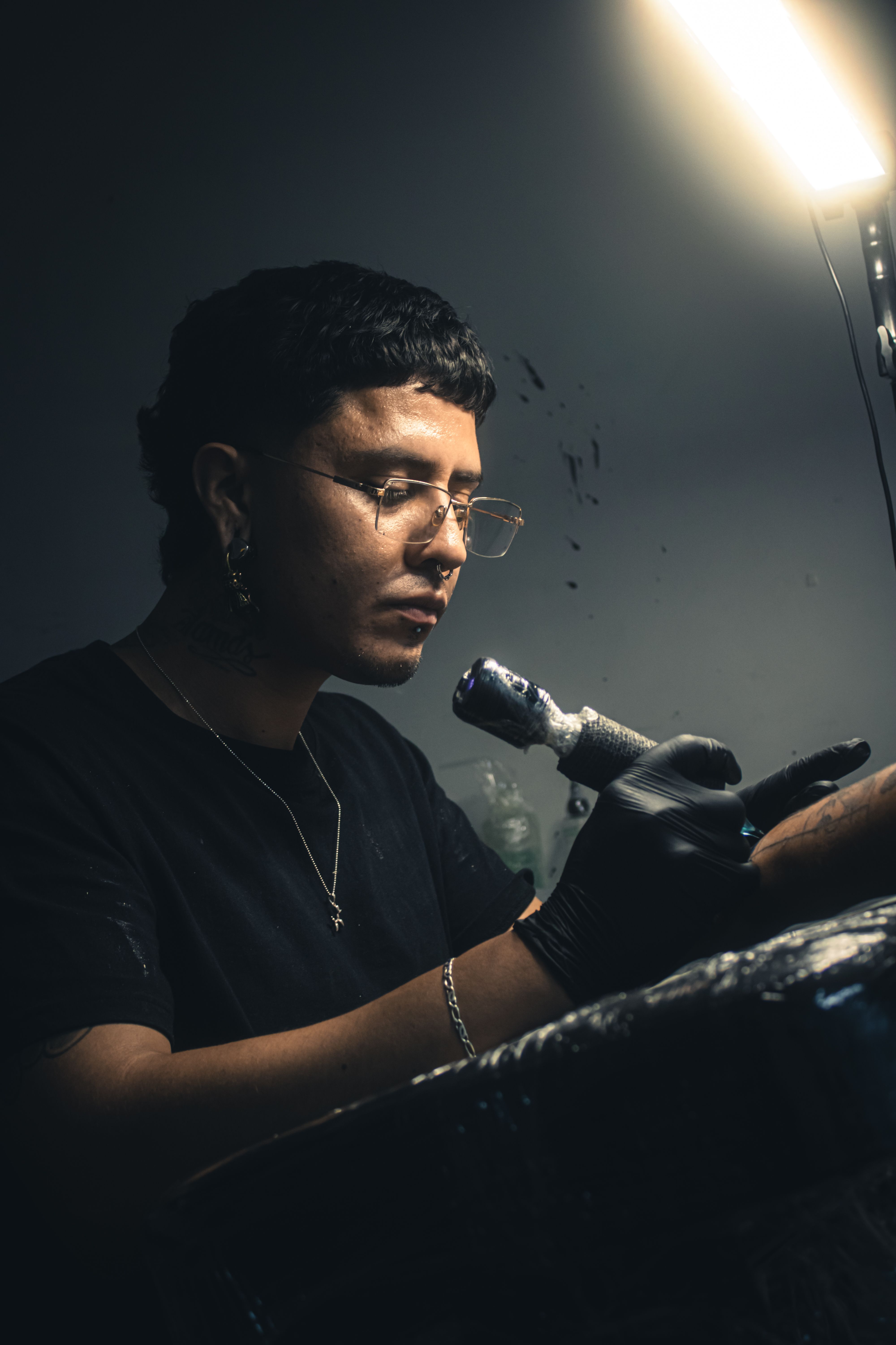 A focused tattoo artist working in a dimly lit studio, crafting detailed skin art.